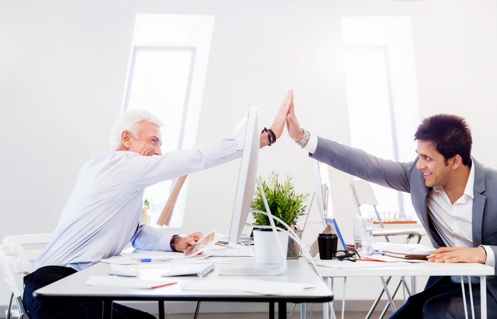 Zwei Menschen schlagen mit den Händen überr einem Schreibtisch ein